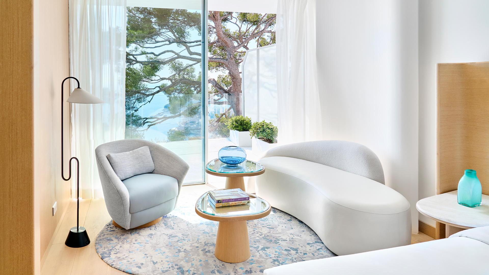 The lounge area of the Corniche Room with an armchair, coffee table and sofa, and the terrace in the background.