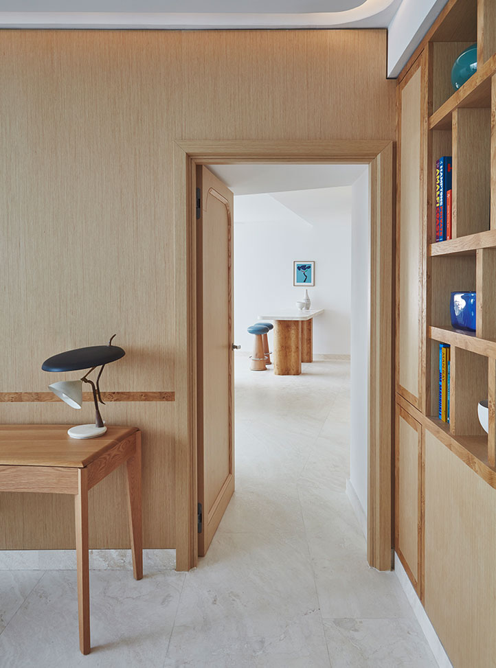 View through an open space in the suite with wooden walls showing the edge of a brown desk with a black lamp on top