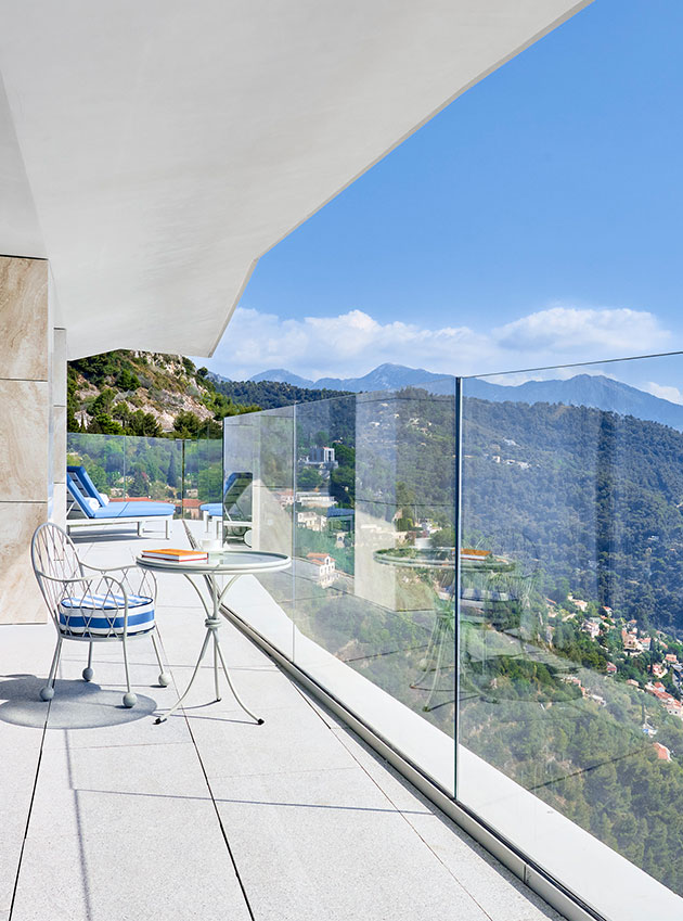 Blue and white striped chairs overlook the glass balcony of the grand sea view suite