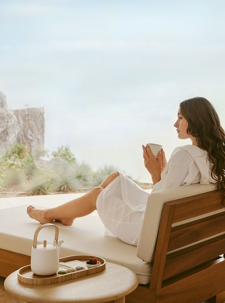 The Maybourne Riviera Spa - Model Laying on Chair Having a Cup of Tea and Looking at the View from the window